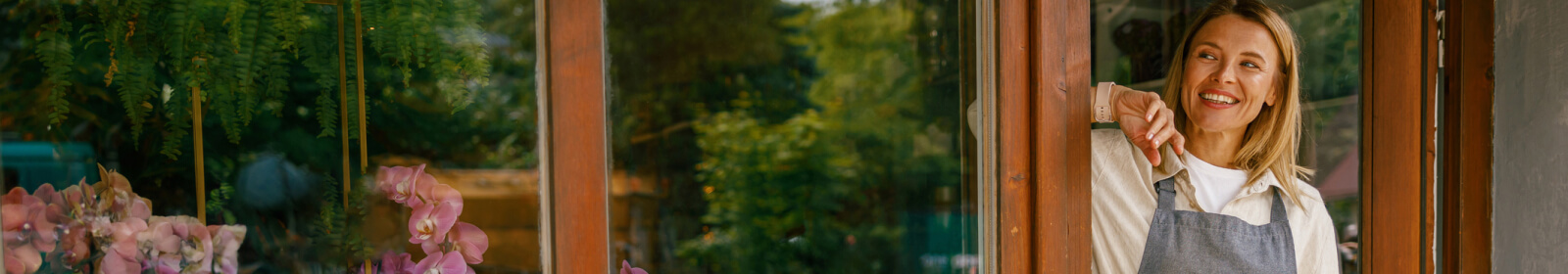 woman in an apron standing outside a floral shop