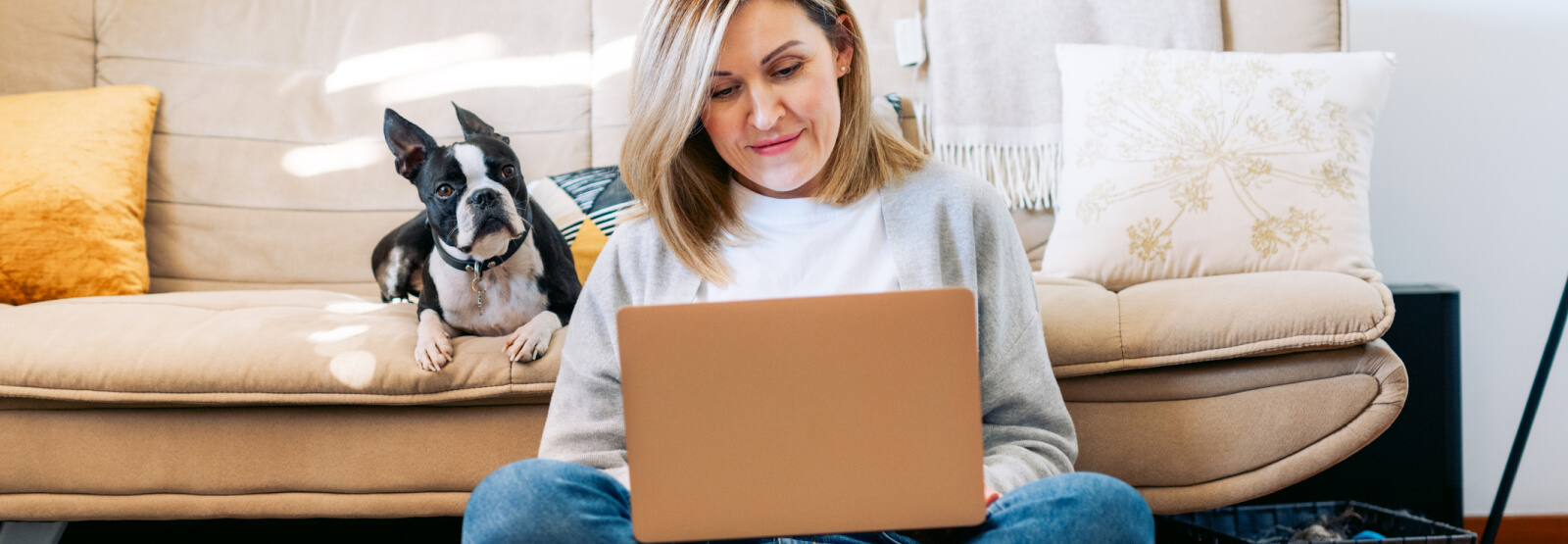 woman using a laptop with her dog behind her