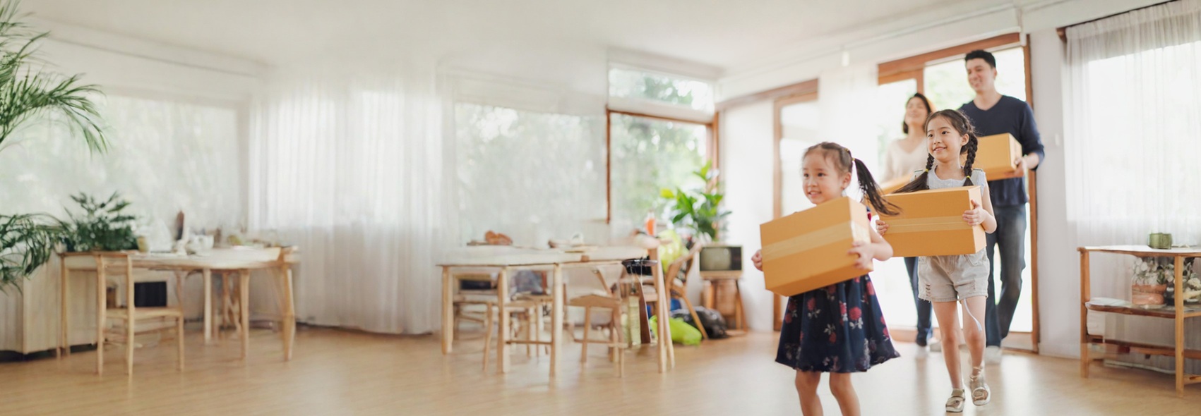 smiling family of four running into their new home with sealed moving boxes
